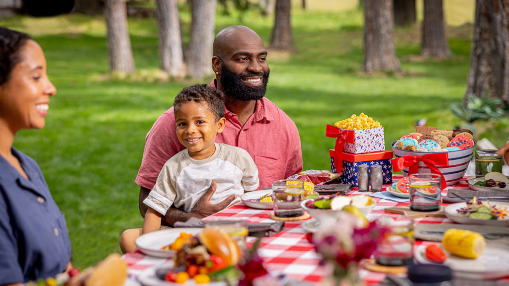 Photo of july birthdays with a father and son sitting at a picnic table.