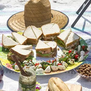 Photo of july recipes with a platter of sandwiches and appetizers at the beach.