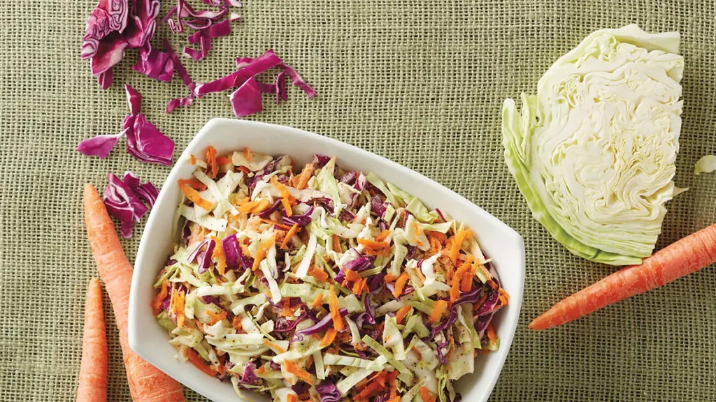 Photo of salads with coleslaw in a bowl with half a cabbage next to it