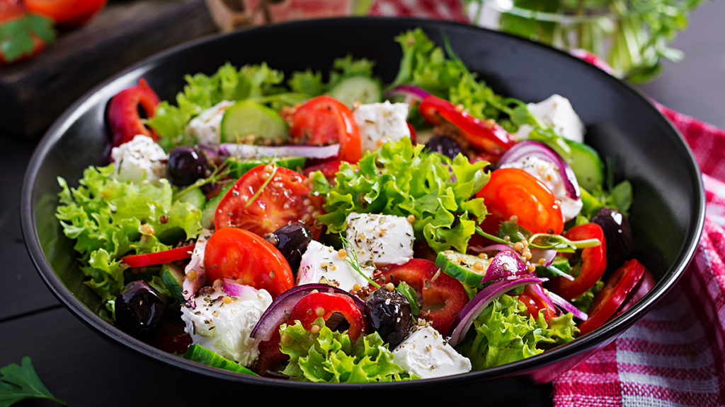 Photo of salads with a Greek salad in a black bowl