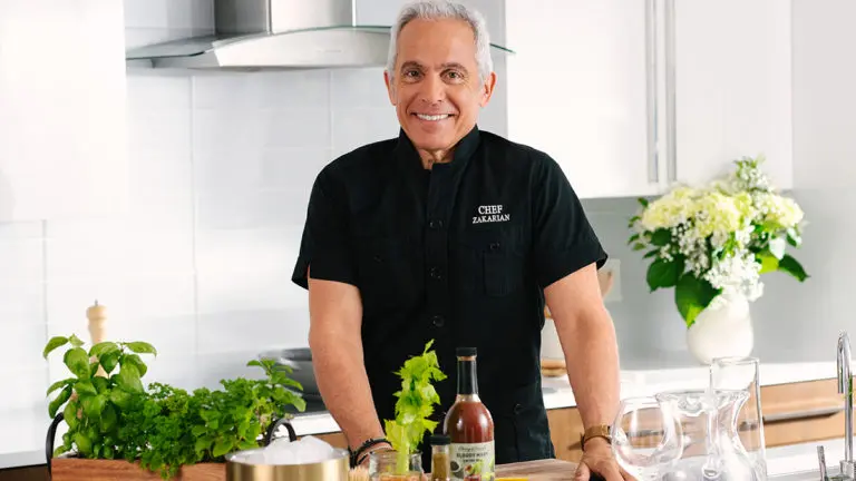Photo of summer entertaining recipes with Geoffrey Zakarian standing in a kitchen.