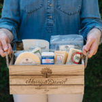 A photo of teacher gifts with someone holding a box of cheese