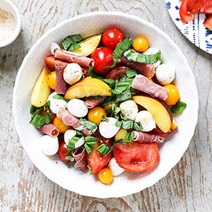 August recipes with a bowl full of peach caprese salad