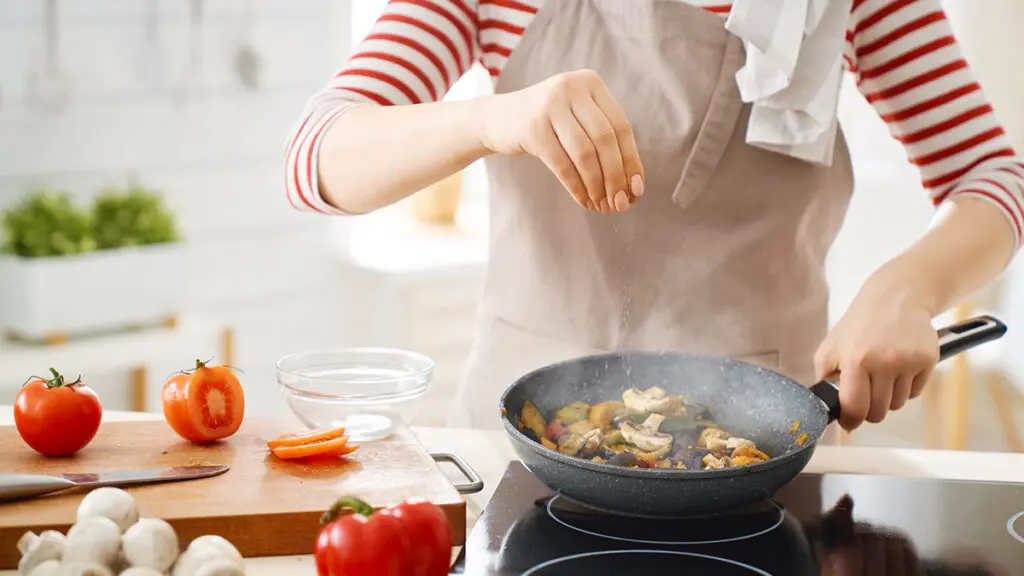 Cooking therapy with someone sprinkling seasoning into a pot on a stove.