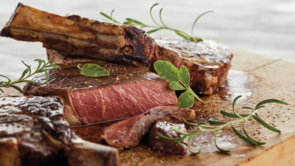 Photo of how to grill with several chunks of cooked meat on a wooden tray.