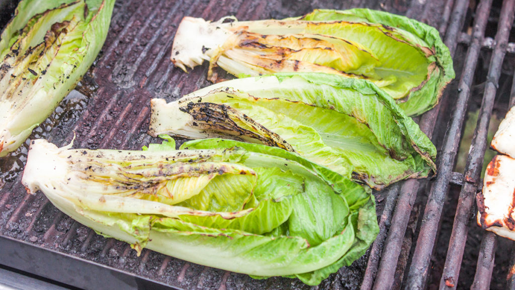 Photo of how to grill with three romaine hearts on a grill.