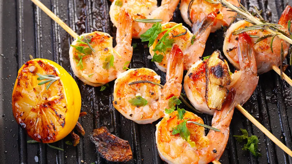 Photo of how to grill with shrimp on skewers grilling on a grate.