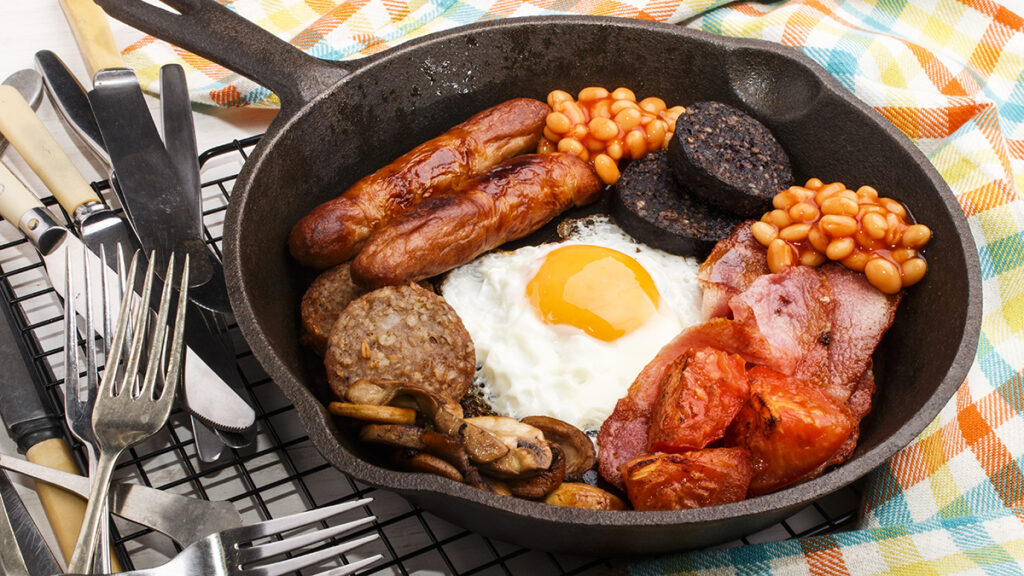 Breakfast meat in a cast iron skillet surrounding a fried egg.