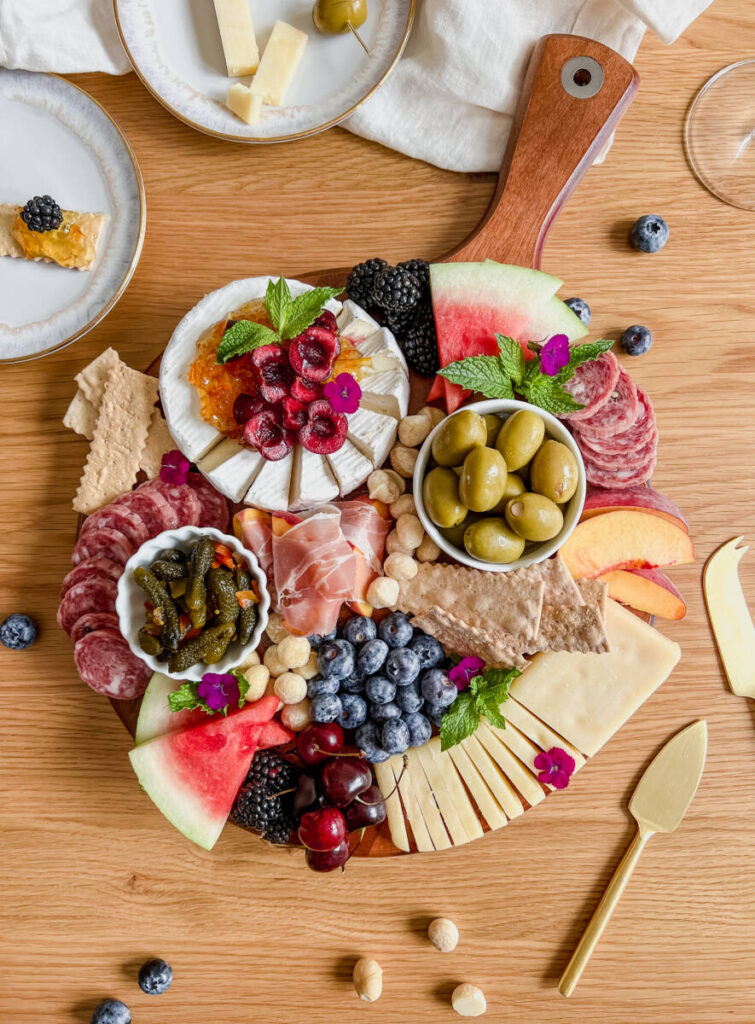 Snack board ideas with a cheese board full of fruit, cheese, meat and crackers.