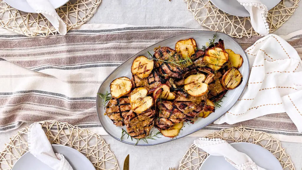 Pork chops with grilled apples on a plate.