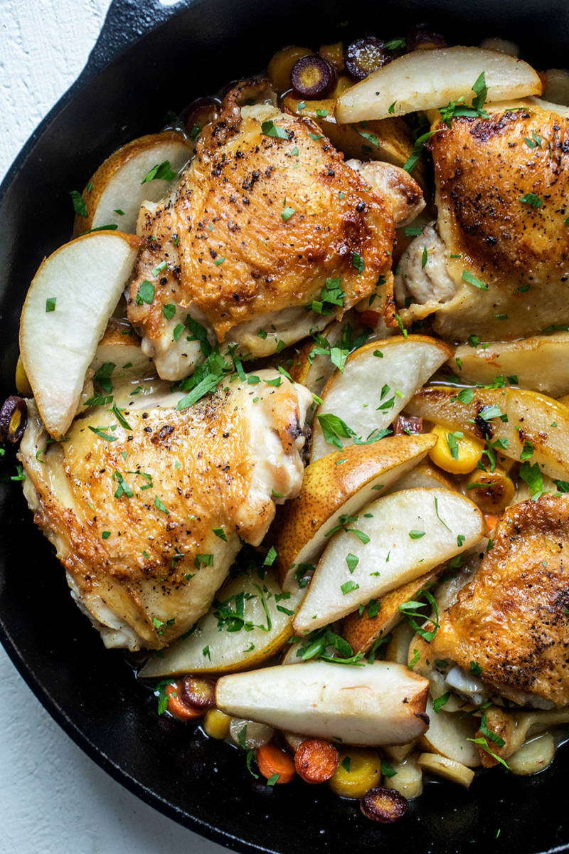 Types of pears with a closeup of a cast iron skillet full of chicken and pear slices.