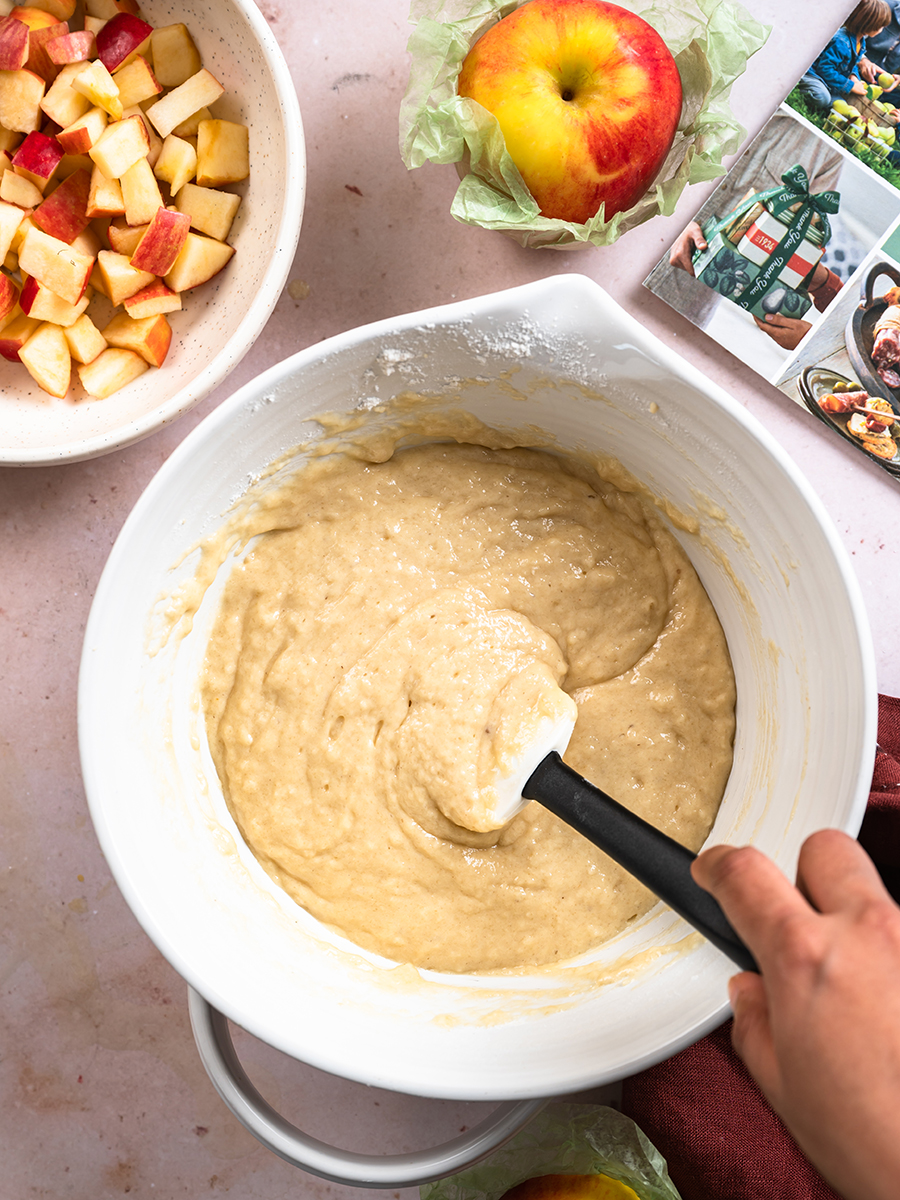 Cinnamon apple cake baking process with a bowl of batter next to a bowl of chopped apples.