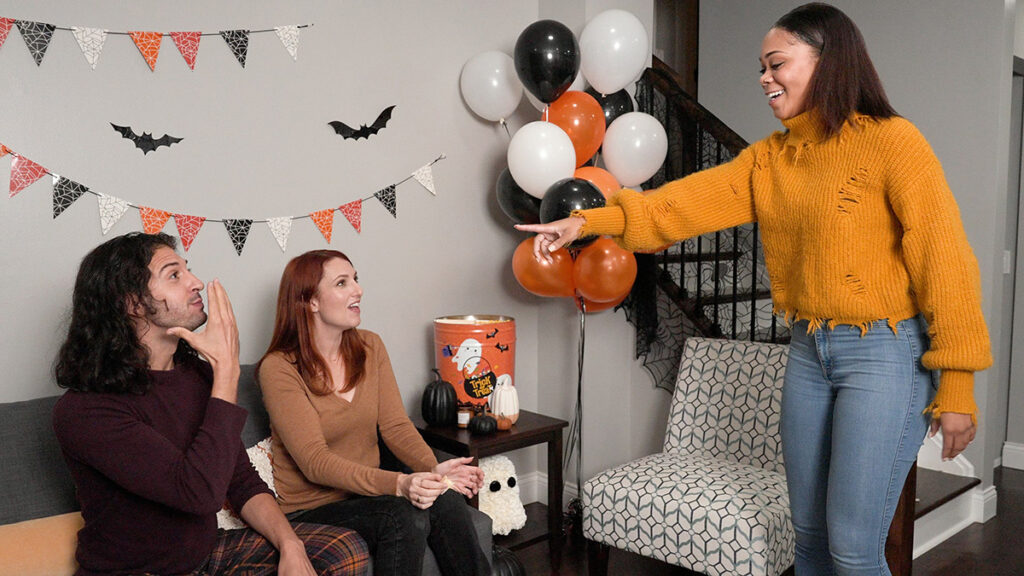 Fall birthday party with three people playing a game in a room decorated for Halloween