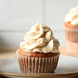 Fall recipes with a pumpkin cupcake topped with frosting on a plate.