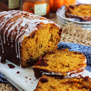 October recipes with a loaf of pumpkin cranberry bread with icing.