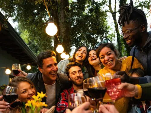 A group celebrating September birthdays and clinking glasses outside.