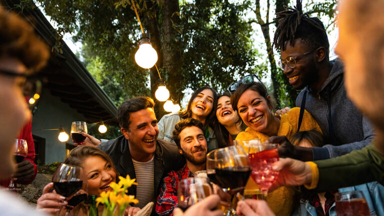 A group celebrating September birthdays and clinking glasses outside.