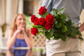 Sweetest Day Gifts. A man holding a bouquet of roses behind his back