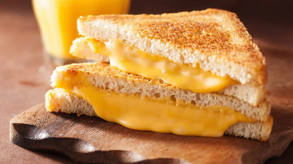 Types of cheese with a grilled cheese on a board.