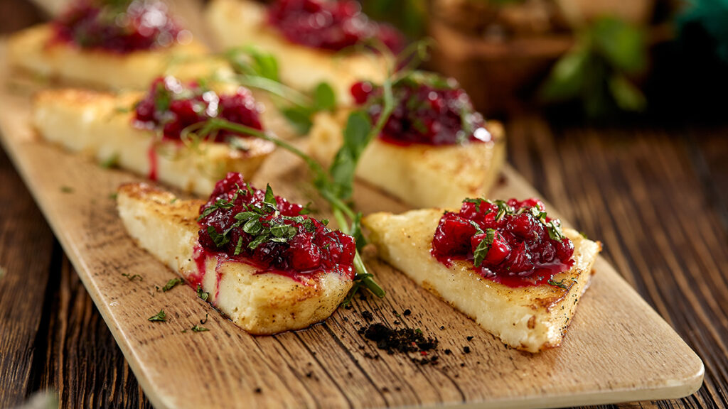 Types of cheese with a plate of halloumi topped with relish and greenery