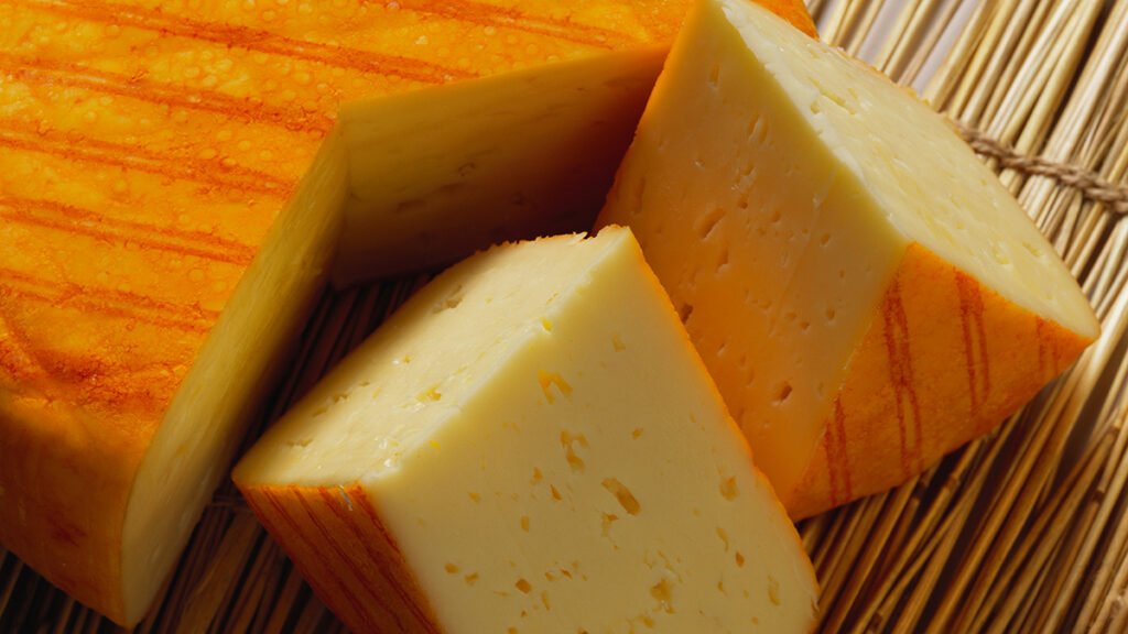 Types of cheese with a closeup of a block of muenster sliced into two smaller chunks.