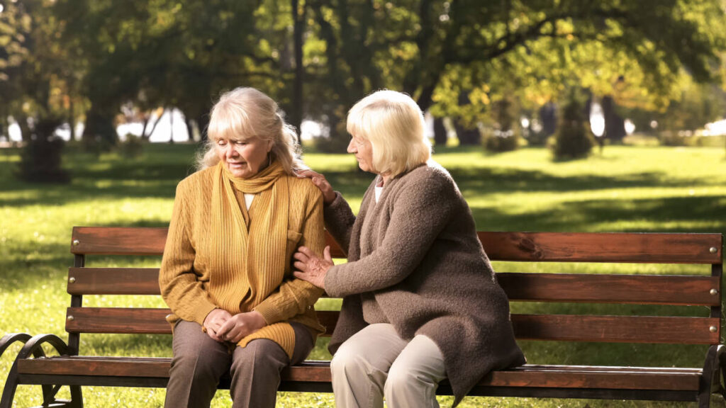 primer año de pérdida con dos mujeres sentadas en un banco del parque.