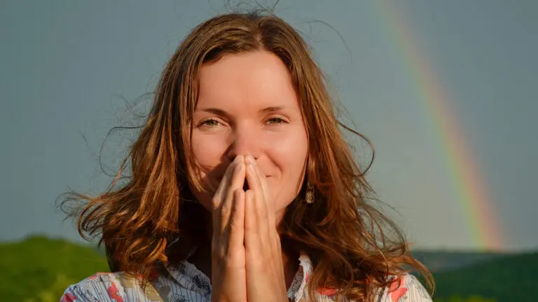 Gratitude practice with a woman looking at the camera with her hands in prayer.