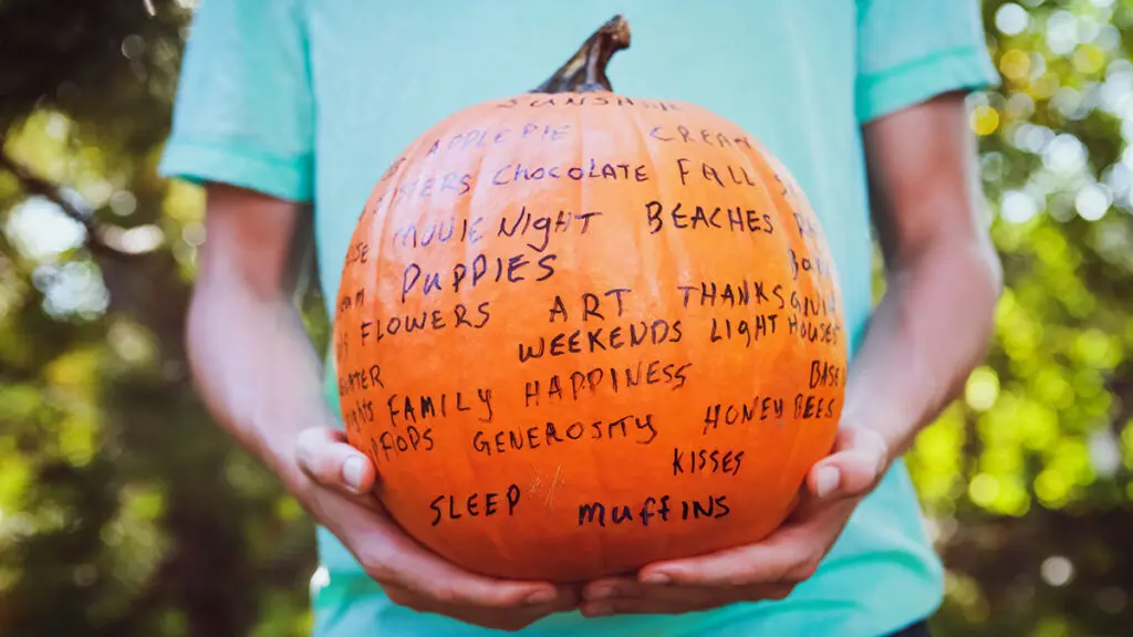 Gratitude with a pumpkin covered in words.