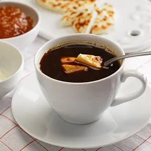 How to make coffee with a cup of Finnish coffee with cheese in it next to a plate of cheese and a bowl of jam.