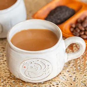 How to make coffee with a cup of coffee with a plate of tea leaves and coffee beans behind it.