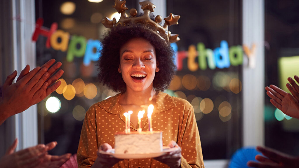 Why birthdays are special with a woman holding a cake with candles while people sing happy birthday.
