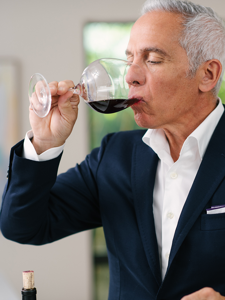 Wine tasting tips with Geoffrey Zakarian drinking red wine from a glass.