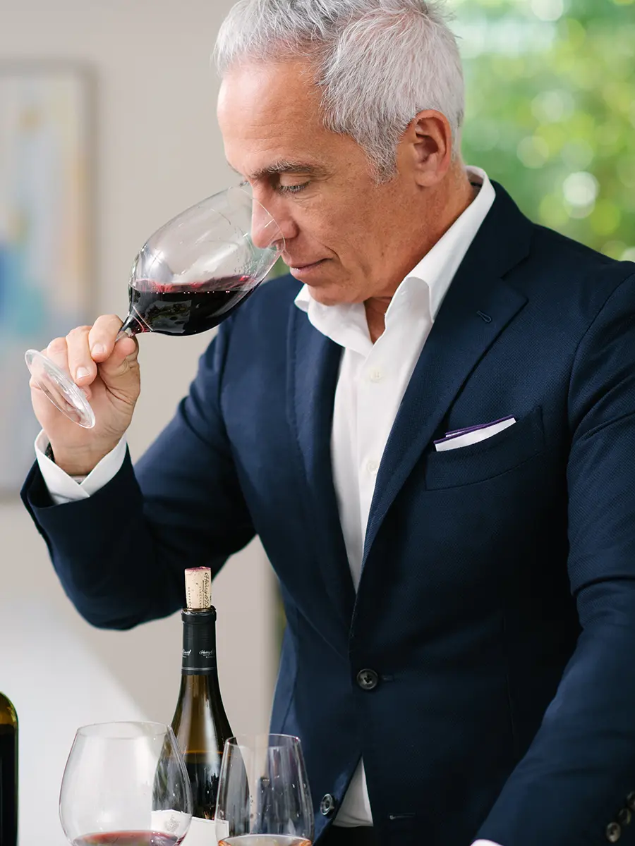 Wine tasting tips with Geoffrey Zakarian sniffing red wine in a glass.