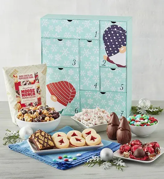 Advent calendar with a collection of Moose Munch, cookies, chocolates and other goodies in front of it.