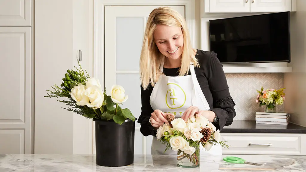 Alice's Table founder arranging a bouquet of flowers in a kitchen.