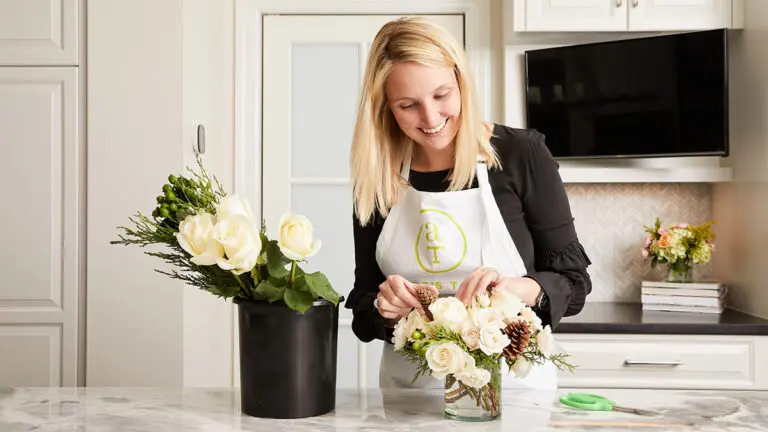 Alice's Table founder arranging a bouquet of flowers in a kitchen.