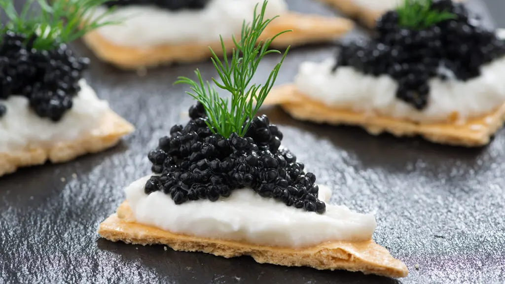 Caviar on crackers with a dill garnish.