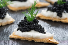 Caviar on crackers with a dill garnish.