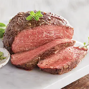 Christmas dinner ideas with a piece of filet mignon on a cutting board with two slices in front of it.