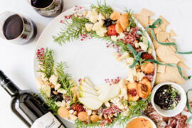 Christmas dinner ideas with an appetizer wreath on a plate next to a bottle of wine and two full glasses.