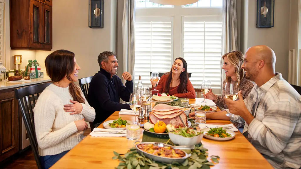 Dinner guest etiquette with a group of adults sitting at a table eating dinner.