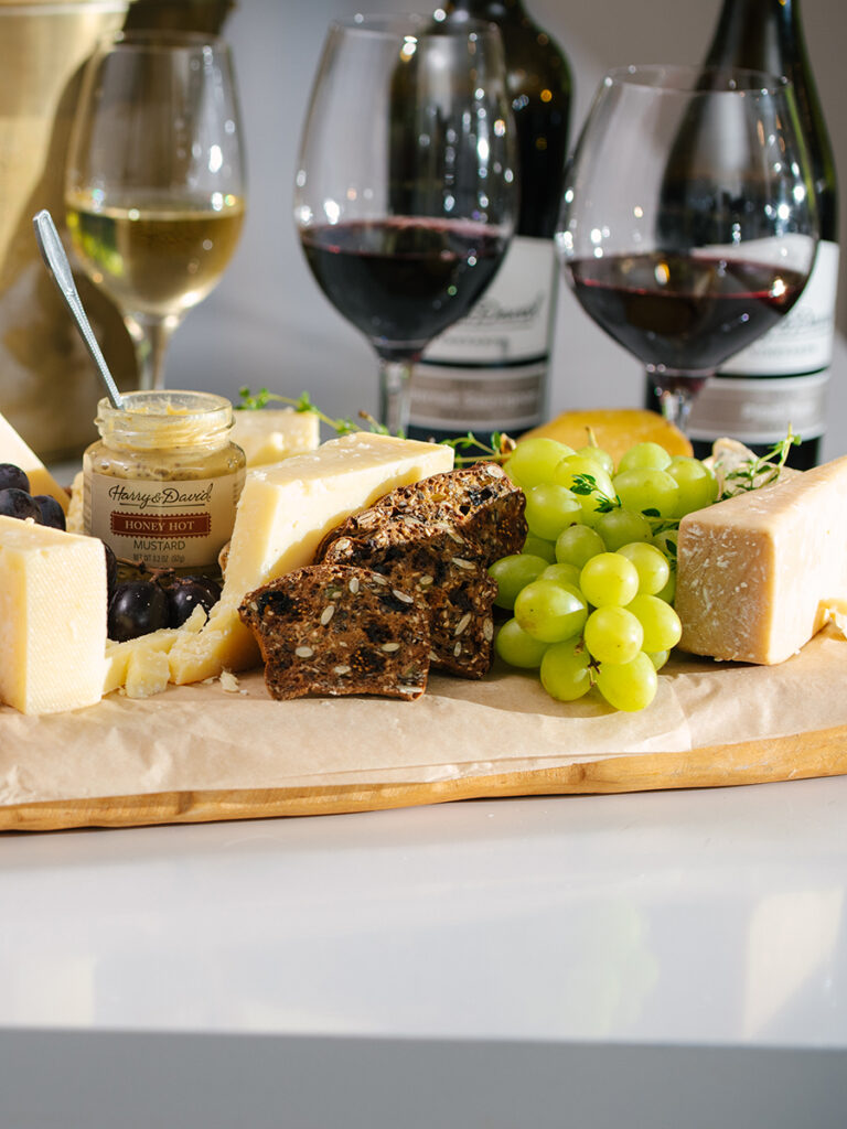 Geoffrey Zakarian wine glasses in the background with a cheese board in the foreground.