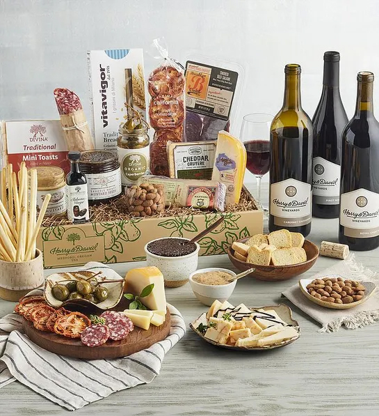 Gifting matrix with a collection of meat, cheese and antipasto with three bottles of wine.