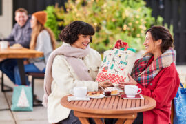 Gifting matrix with two women sitting outside exchanging presents.