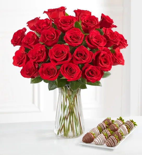 Gifting matrix with a bouquet of red roses next to a plate of chocolate covered strawberries.