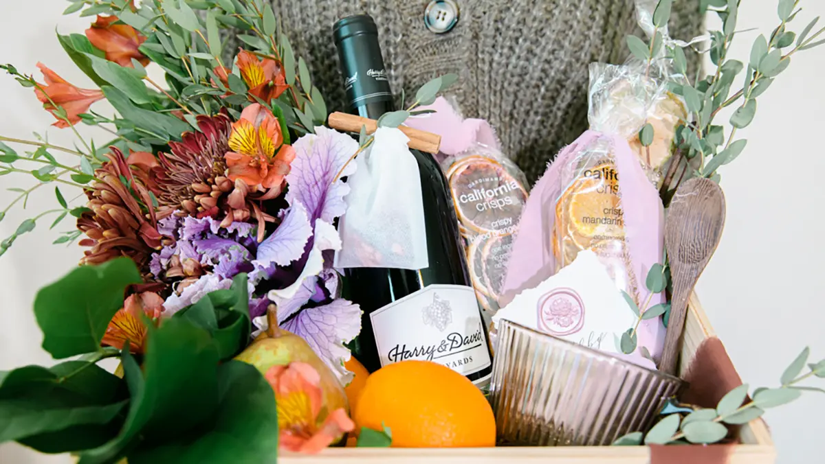 Hostess gift ideas with a basket of wine, flowers, and fruit.