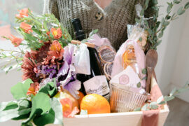 Hostess gift ideas with a basket of wine, flowers, and fruit.