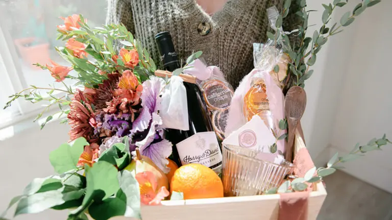 Hostess gift ideas with a basket of wine, flowers, and fruit.