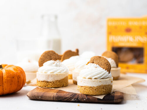 No bake pumpkin cheesecakes on a board topped with pumpkin cookies.