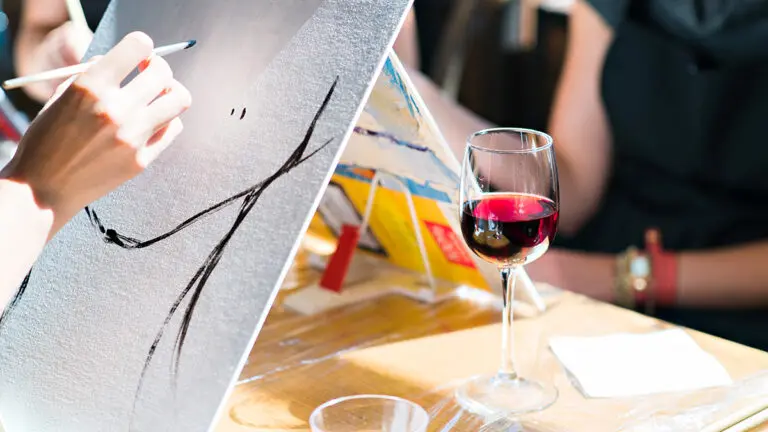 Paint and sip party with a glass of wine next to a canvas that's being painted.